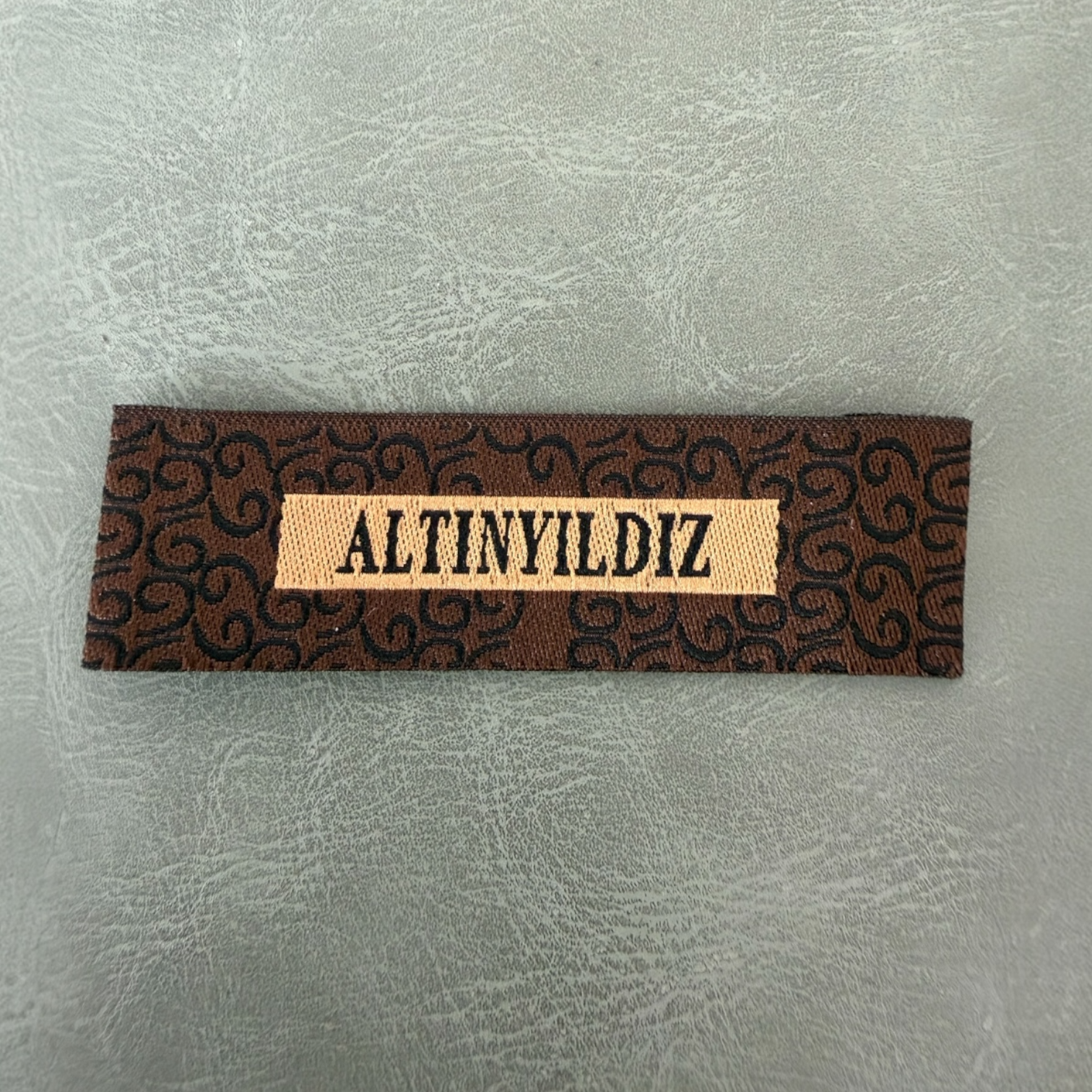 Жакардов тъкан етикет LBL 0042 6.5 x 2 см – уникален марков дизайн с тъкани букви, мек премиум стил, с лого, MOQ 1000 бр Етикети