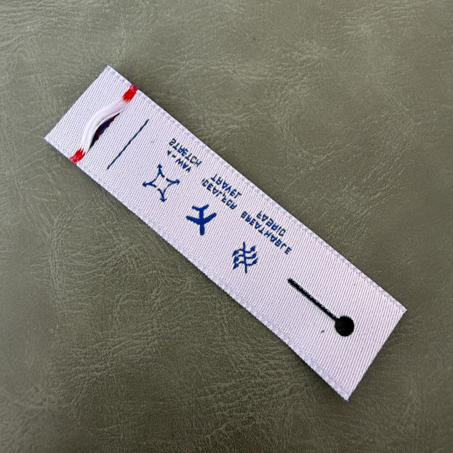 Жакардов тъкан етикет LBL 0043 8 x 2 см – уникален дизайн с отвор за копче, тъкани букви, мек премиум стил, с лого, MOQ 1000 бр Етикети