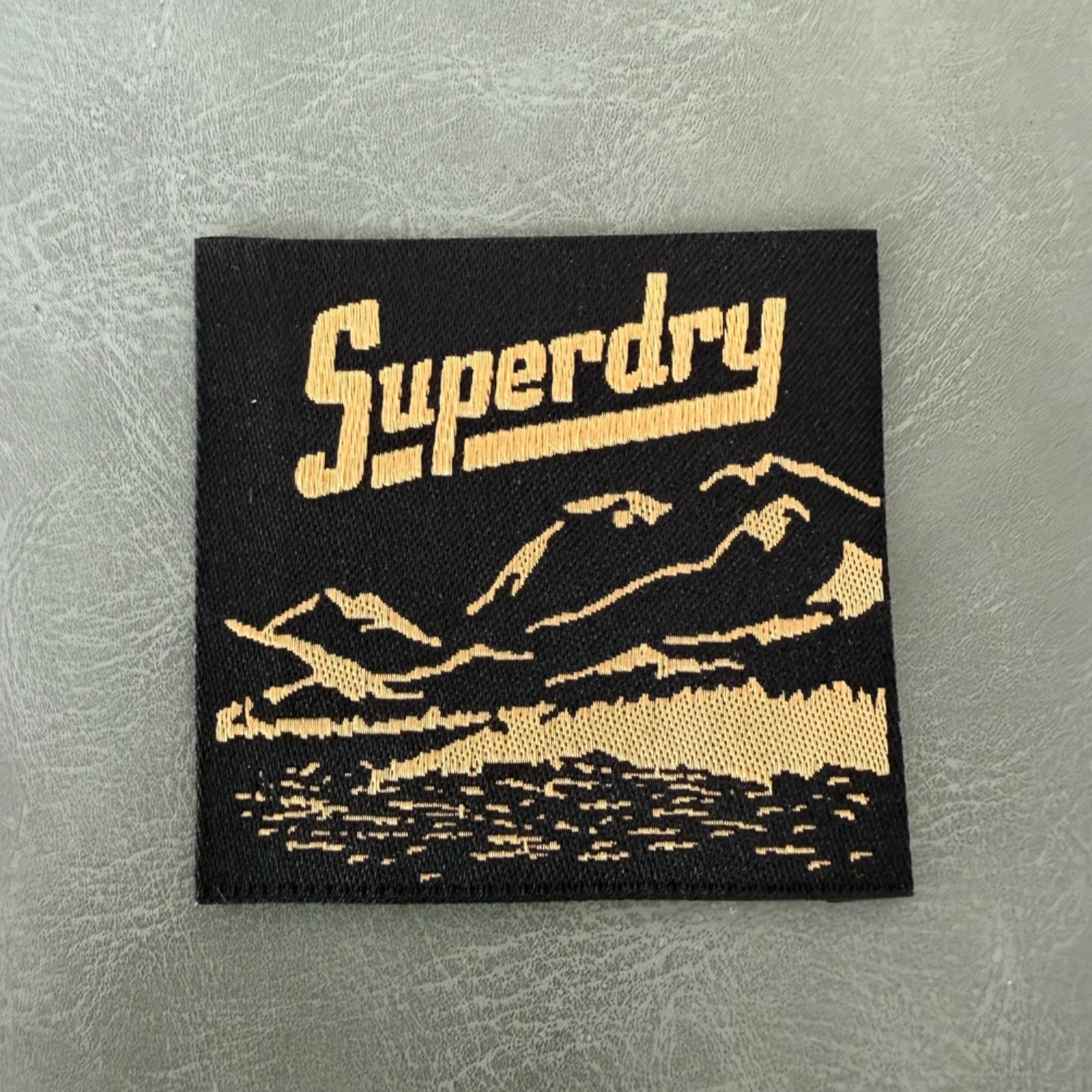 Жакардов тъкан етикет LBL 0046 5 x 5 см – черна основа със златни букви, премиум дизайн, мек стил, с лого, MOQ 1000 бр Етикети