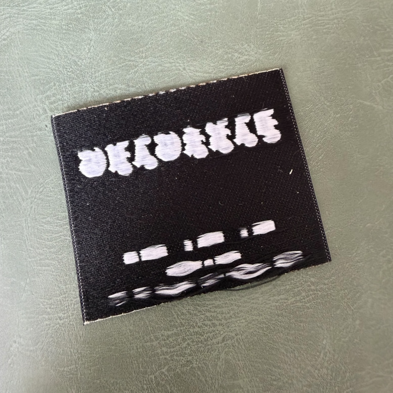 Жакардов тъкан етикет LBL 0055 6 x 5 см – бяла основа с черни букви, мек премиум дизайн, с лого, MOQ 1000 бр Етикети