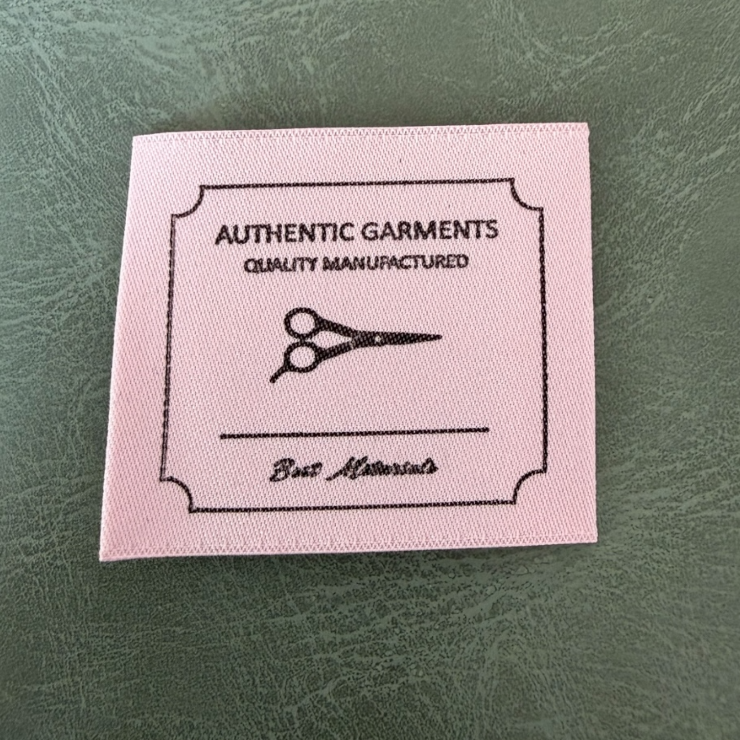 Жакардов тъкан етикет LBL 0058 4 x 3.5 см – розова основа с черни букви, мек премиум дизайн, с лого, MOQ 1000 бр Етикети