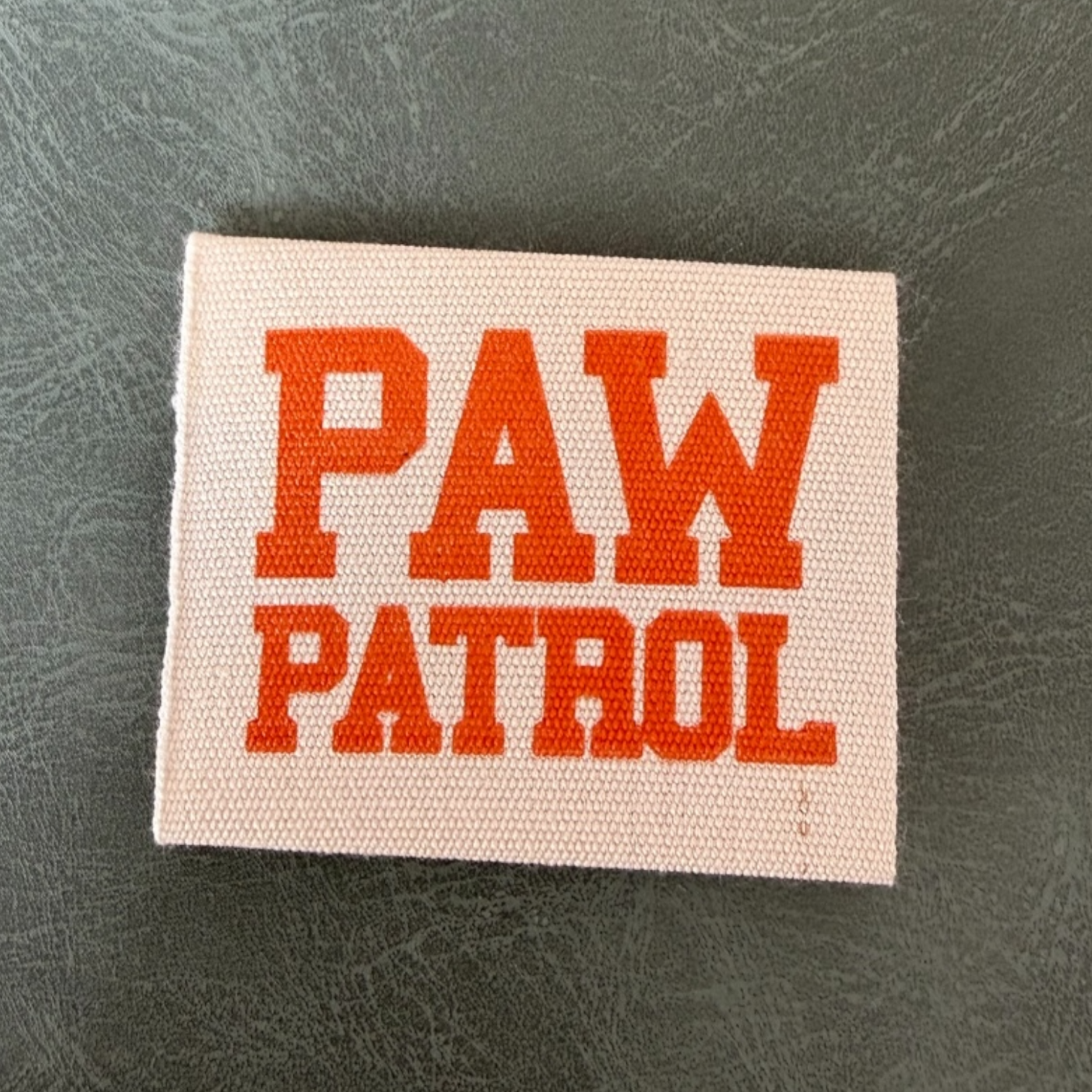 Печатан канвас етикет LBL 0064 4 x 4 см – с оранжеви букви, мек премиум дизайн, с лого, MOQ 1000 бр Етикети